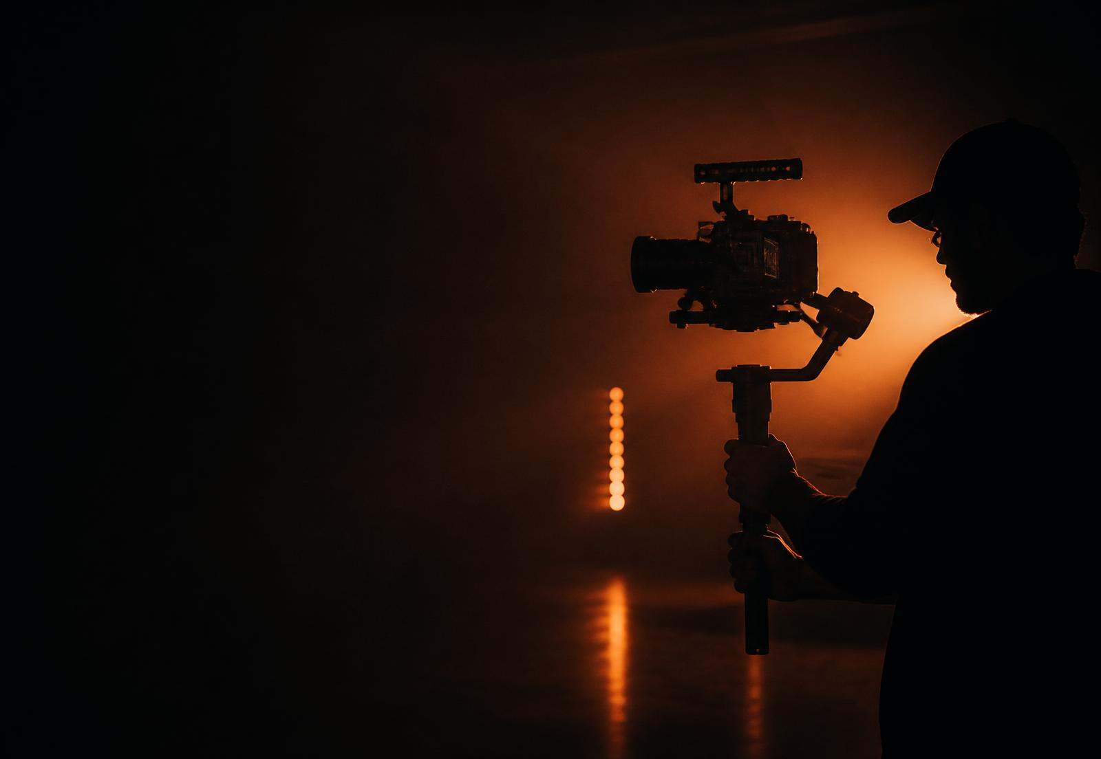 Cinematographer operating a gimbal-mounted cinema camera in a dark studio